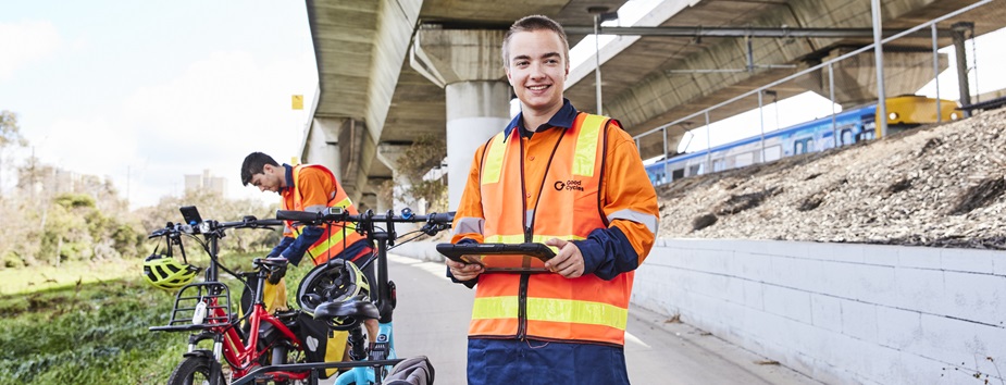 Young man working outside by the road in a high-vis orange shirt, happy and smiling