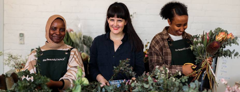 Three young women in frame holding and tending to flowers
